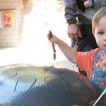 Child plays with metal drum outdoors