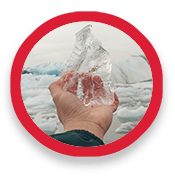 A hand holds up chunk of jagged ice, with icebergs in the background.
