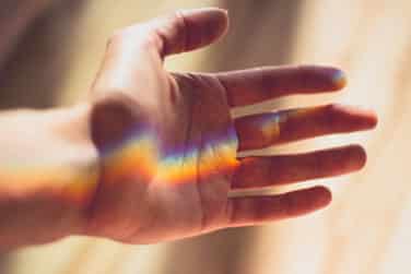 Rainbow light shines on open hand.