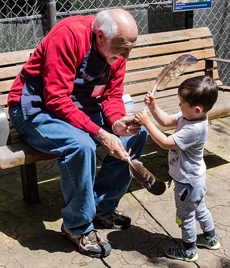 Volunteer shows bird feather to young visitor