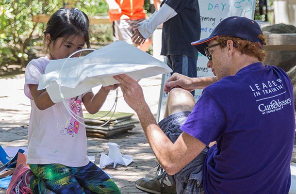 Leadership in Training volunteer assists girl with shaping cloth for experiment