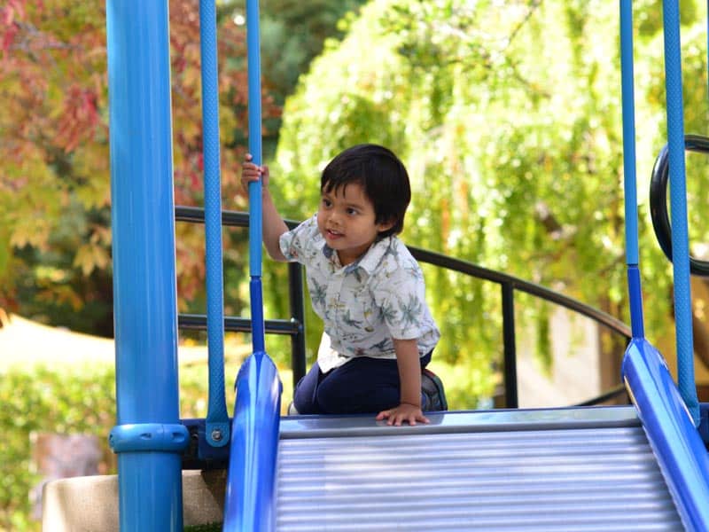 Child sits at the top of a slide ramp