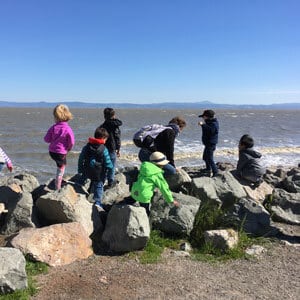 Kids hiking over rocks at the shoreline
