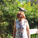 Volunteer Daria Jow with a bird on her head, smiling in our Aviary.