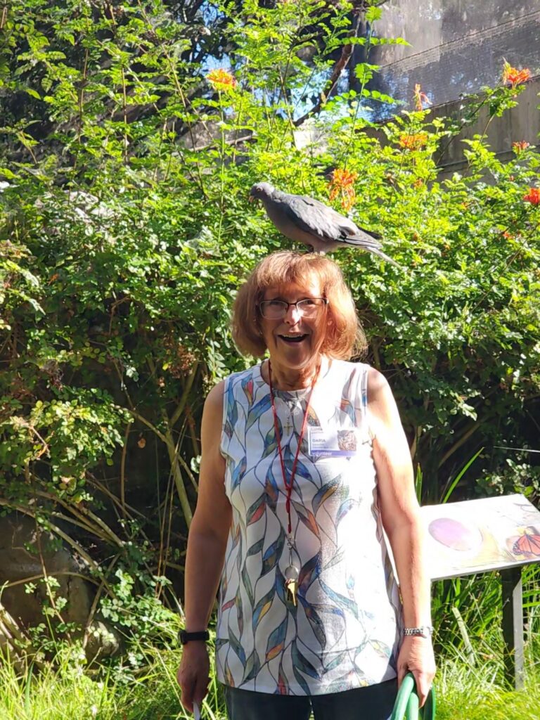 Volunteer Daria Jow with a bird on her head, smiling in our Aviary.