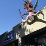 The octopus alebrije suspended on the roof of CuriOdyssey to the right of the entrance. The sculpture is large and multicolored.