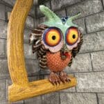 Alebrije sculpture of an owl on a perch. This piece is multicolored.