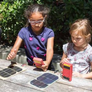 Two children sit at picnic table with solar meters